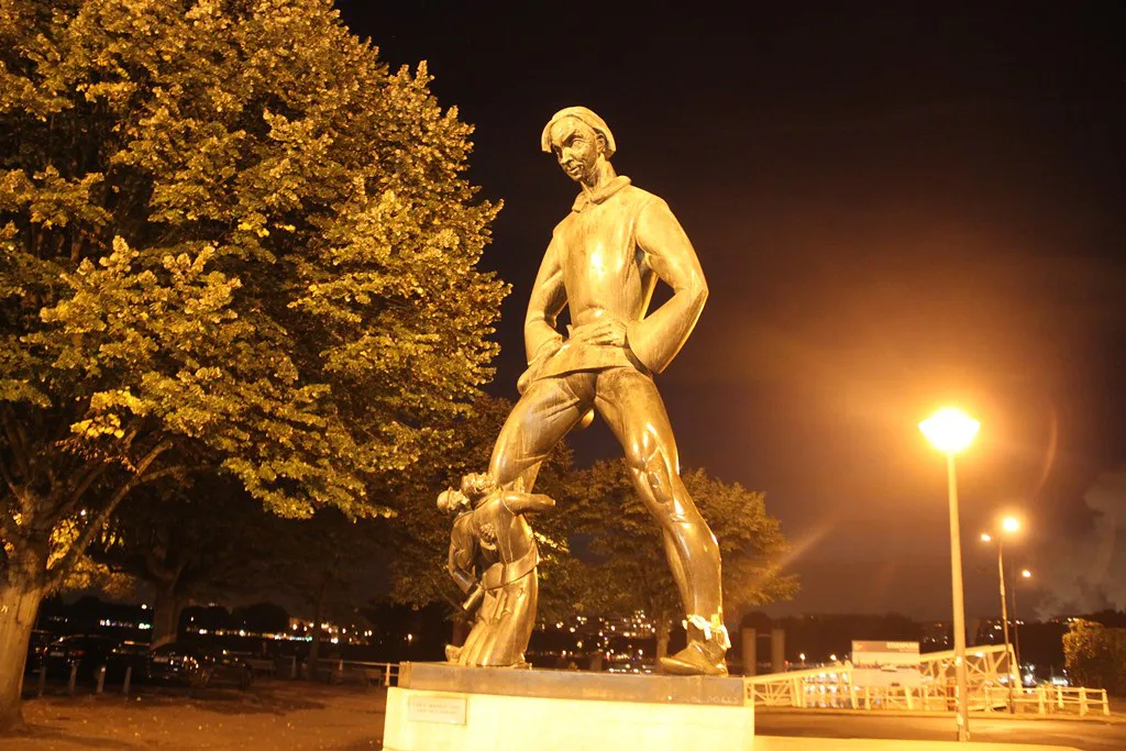 A bronze statue by Het Steen lit at night, Antwerp.