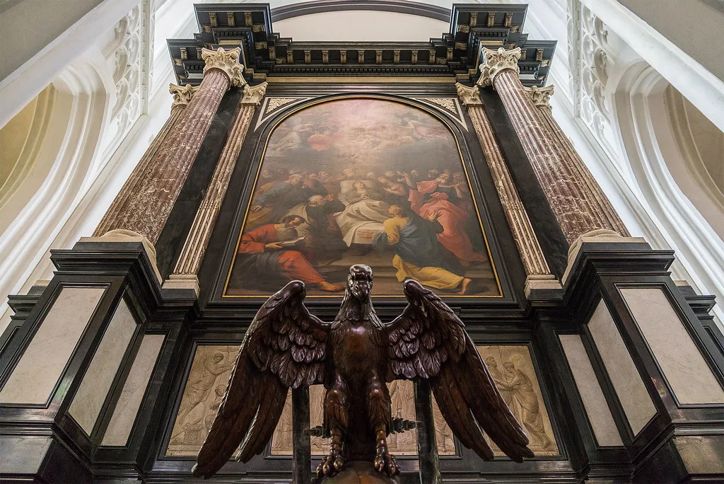 A carved eagle beneath a painted altarpiece in an Antwerp church.