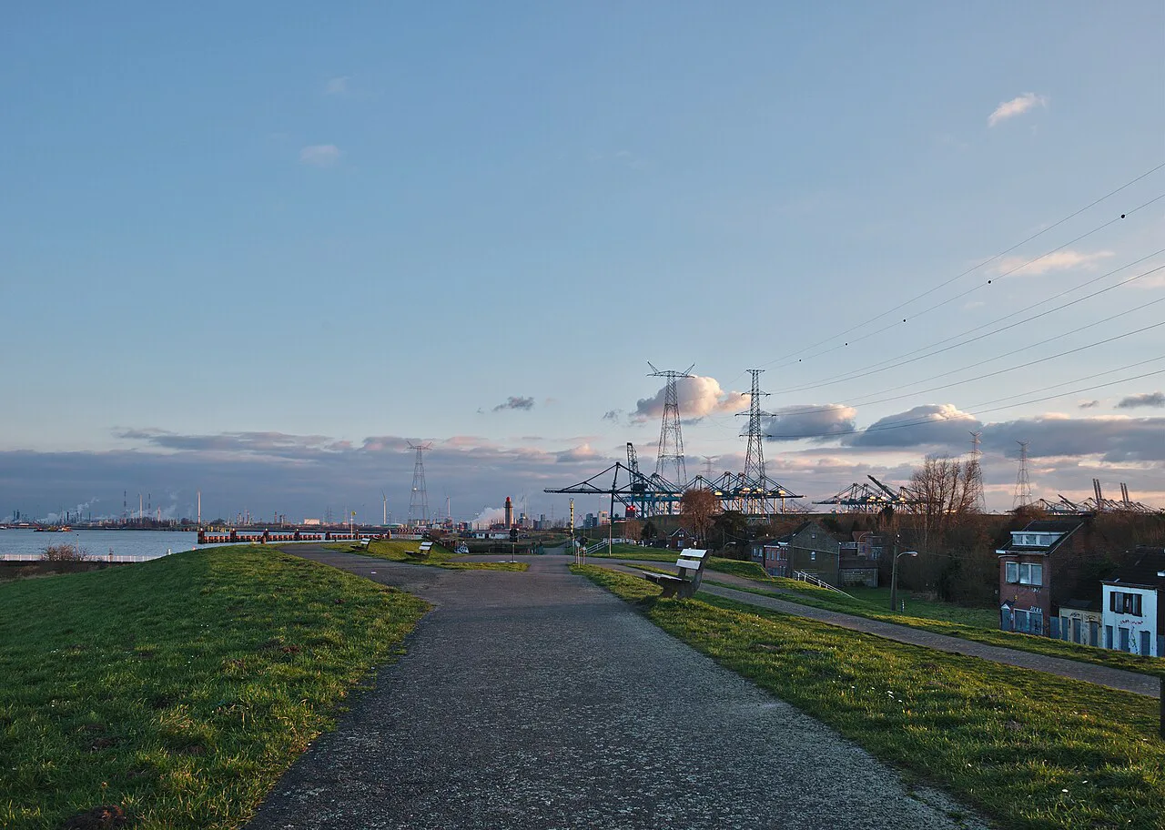 A walkway along the Scheldt at Doel, with the cranes of the Port of Antwerp on the horizon.