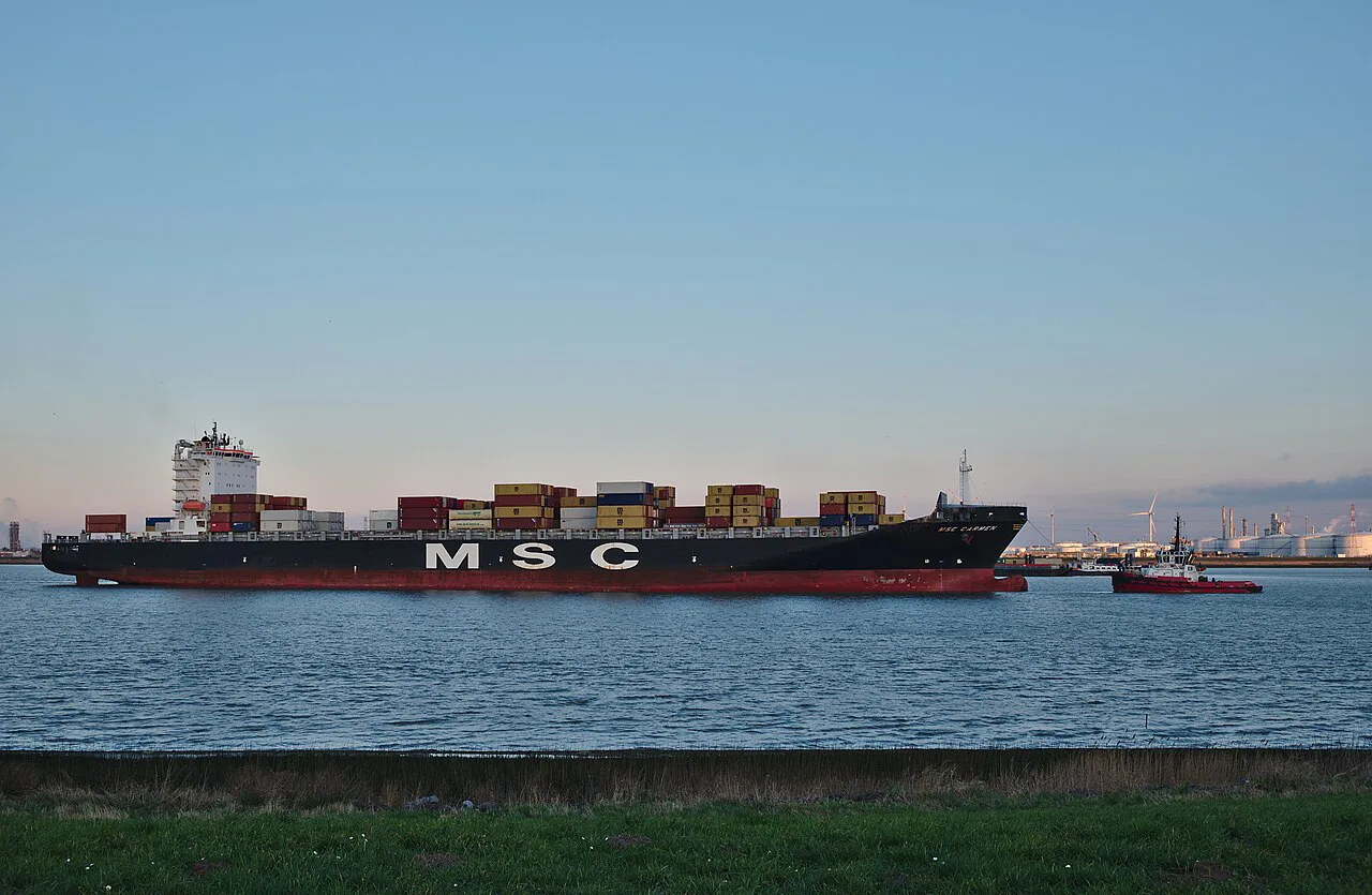 A container ship being towed along the Scheldt towards the Port of Antwerp, seen from Doel.