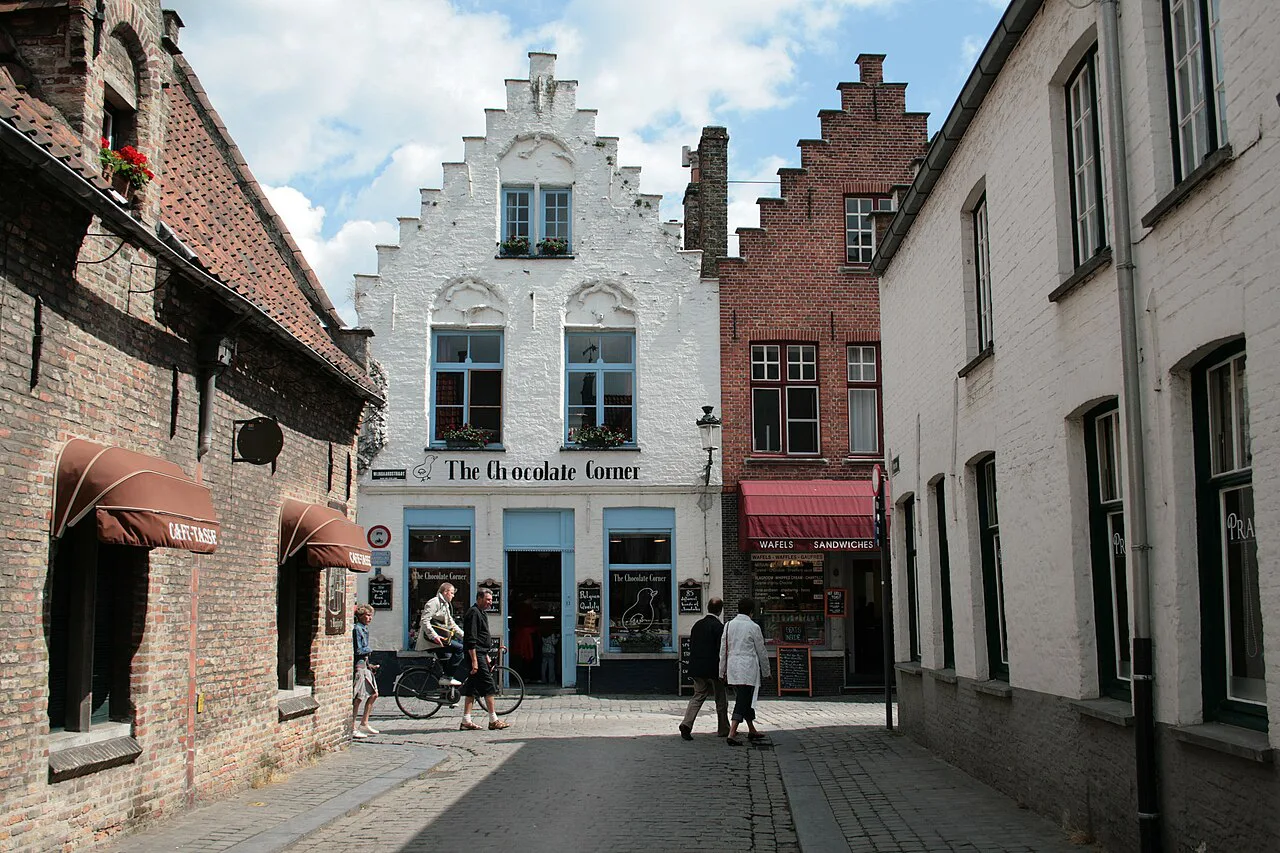 The Chocolate Corner shop on Wijngaardstraat in Bruges, framed by stepped-gable houses.