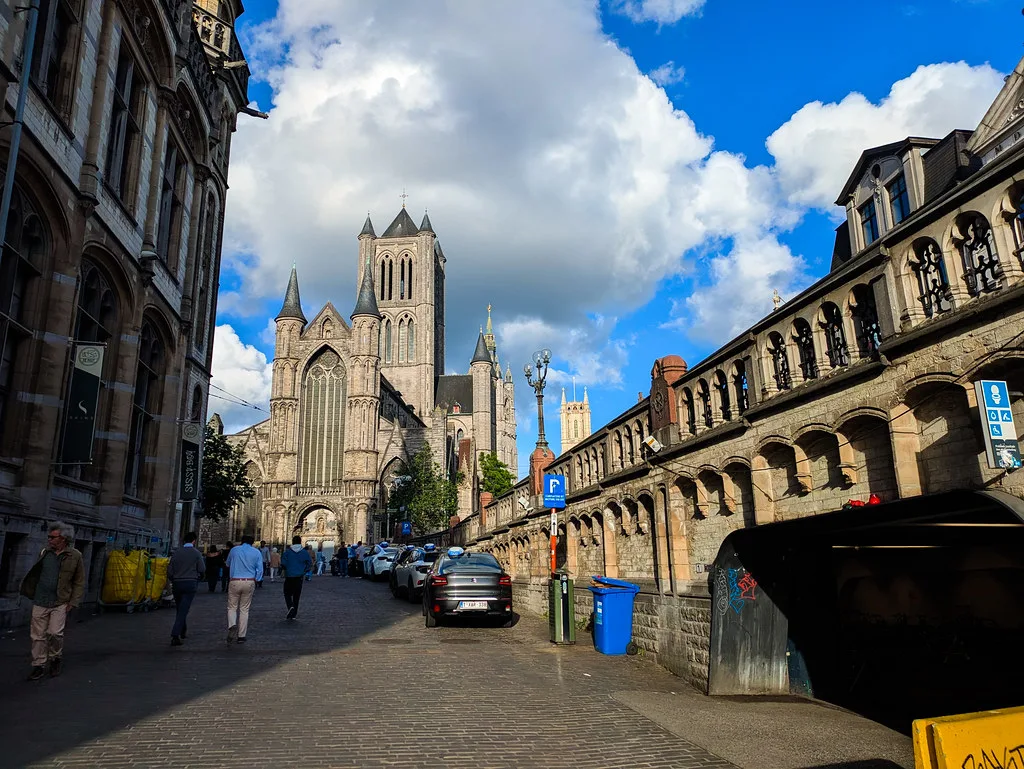 A cobbled street leading towards Saint Nicholas' Church in central Ghent on a sunny day.