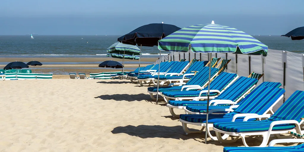 Blue sun loungers and parasols on the beach at De Haan on the Belgian coast.