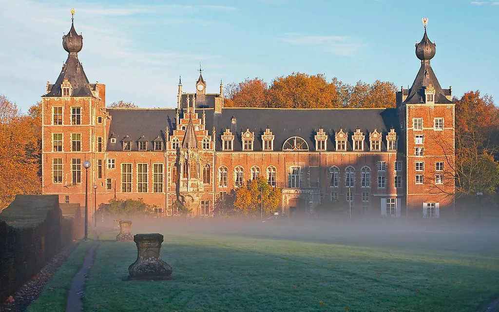 Arenberg Castle at Heverlee near Leuven, with autumn trees and morning mist.