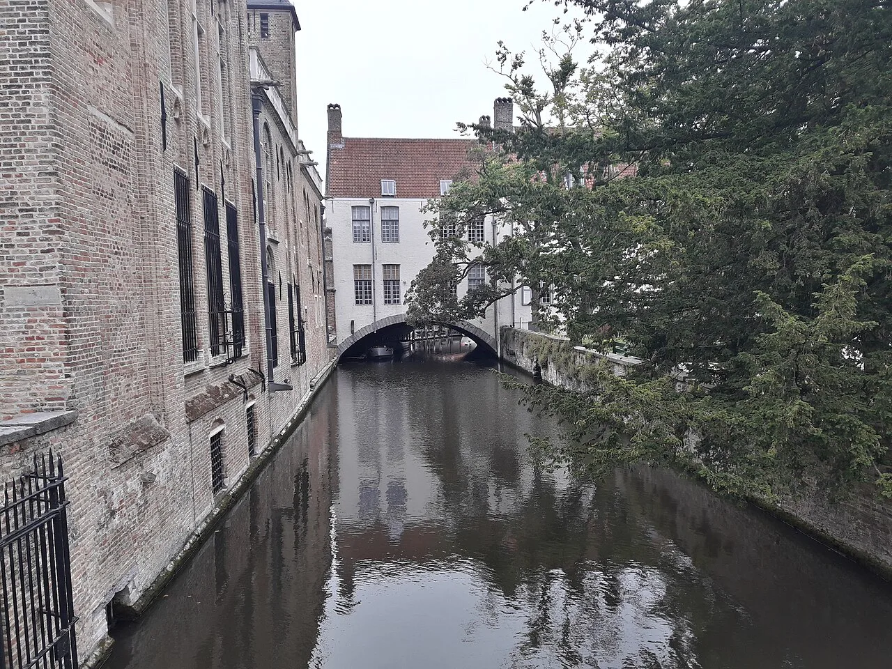 A quiet canal between brick houses in central Bruges.