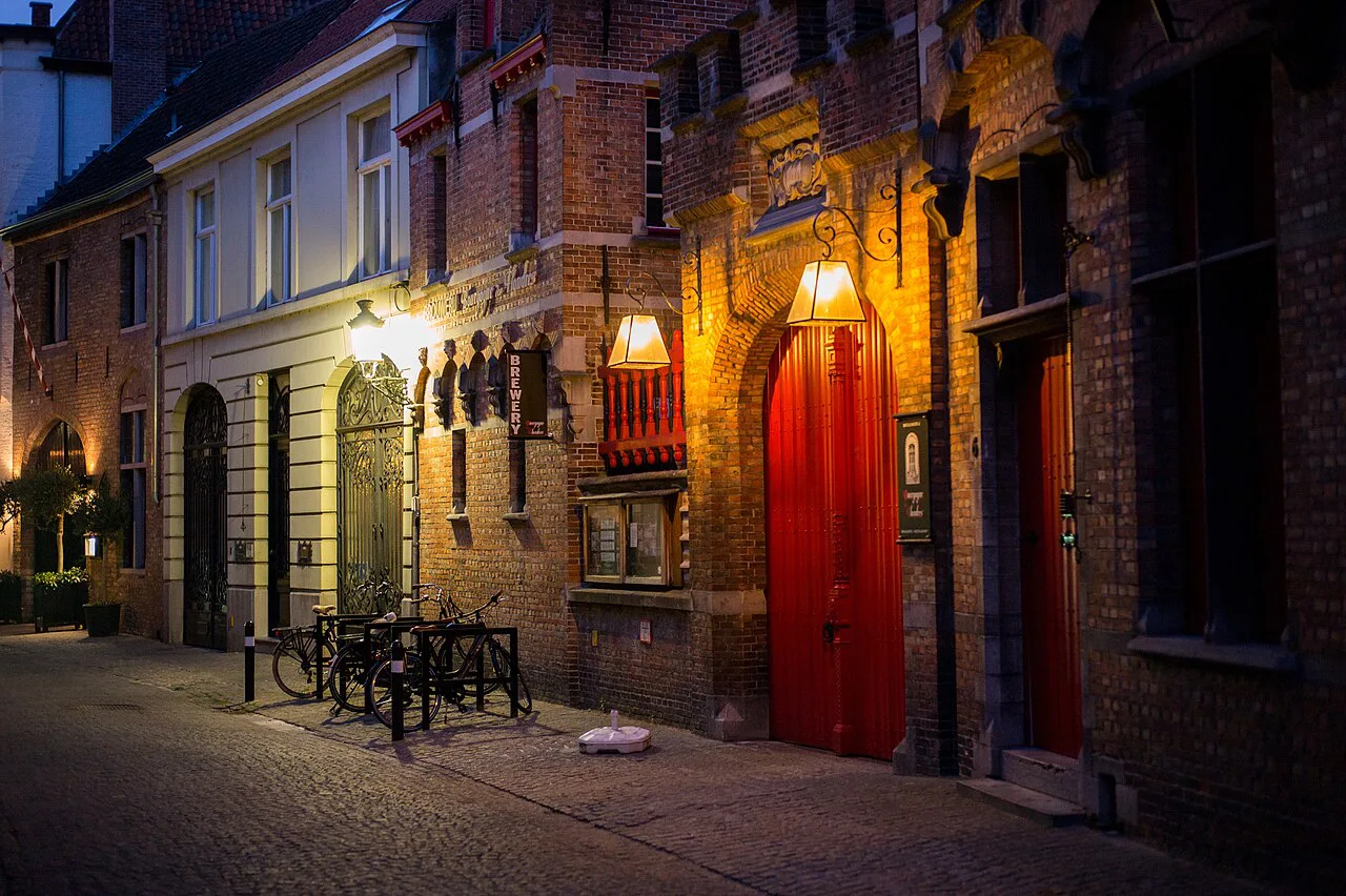 A lamplit brick street at dusk in Bruges.