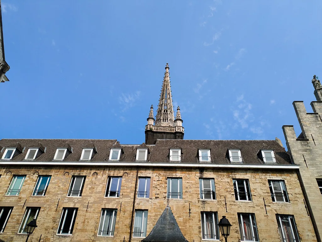 A stone building beneath a Gothic spire in central Leuven.