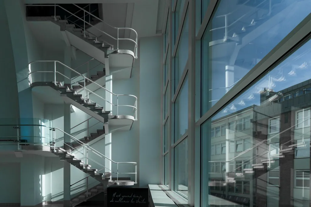 An interior staircase and glass wall at La Cité Miroir in Liège.