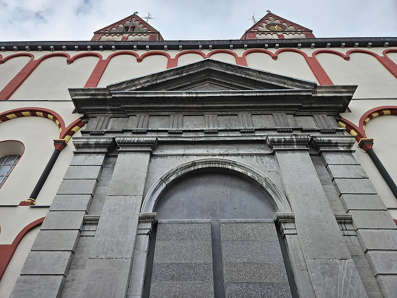 A classical portal on the red-and-white façade of the Collegiate Church of Saint-Barthélemy, Liège.