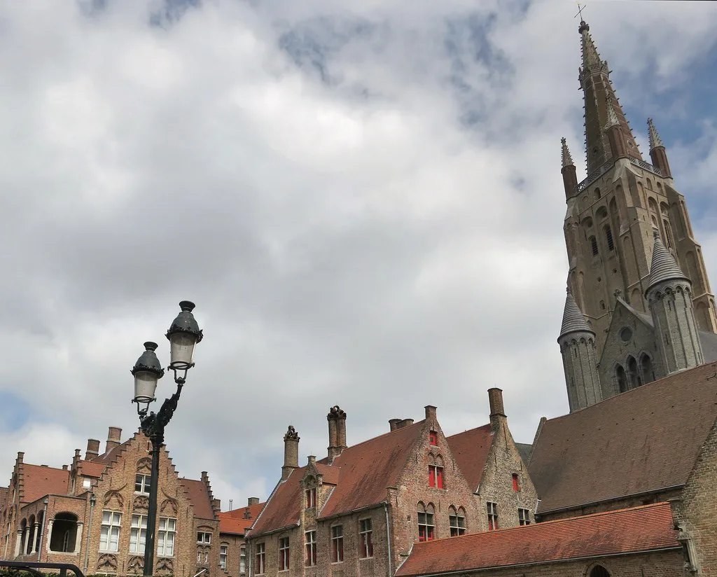 The tower of the Church of Our Lady above brick houses, Bruges.