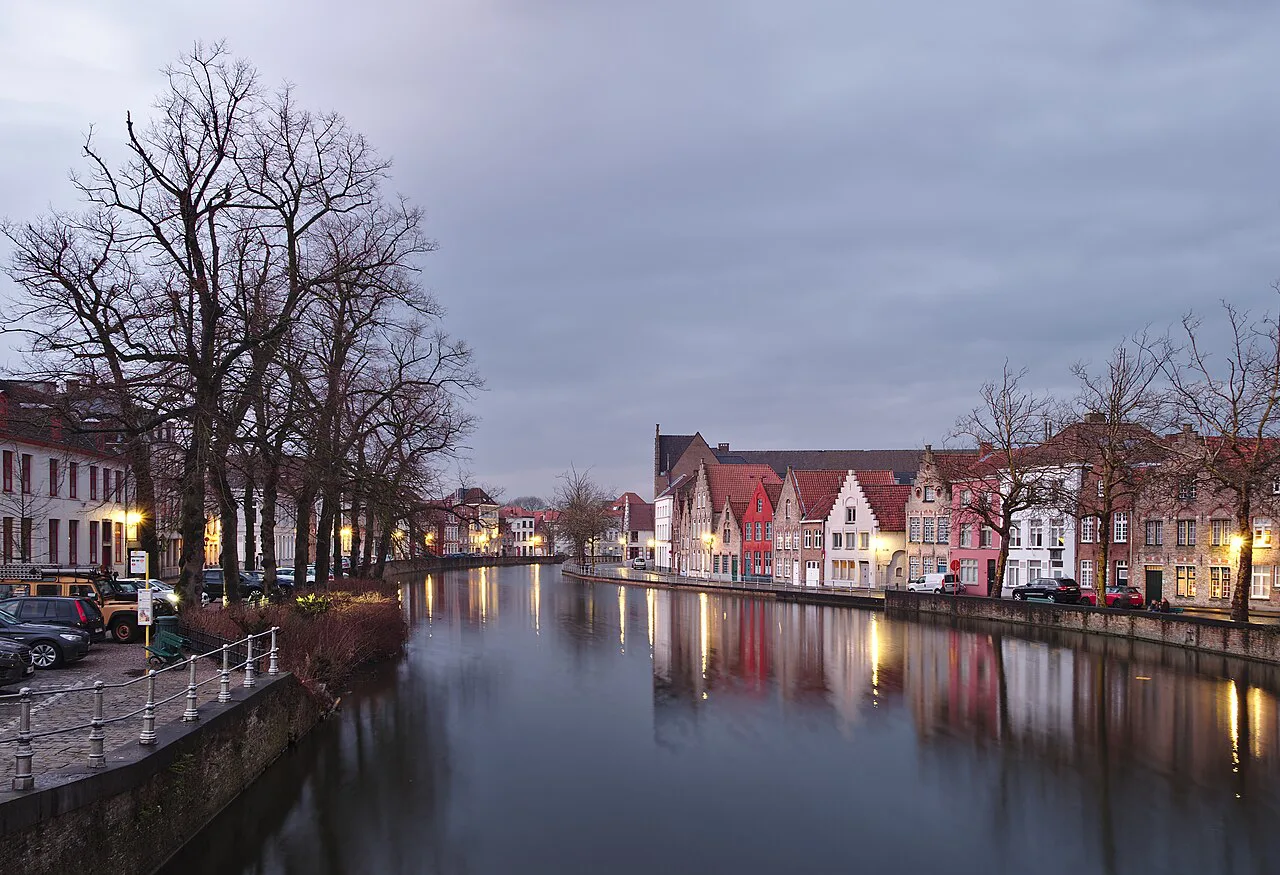 Houses reflected in a canal at dusk in Bruges.