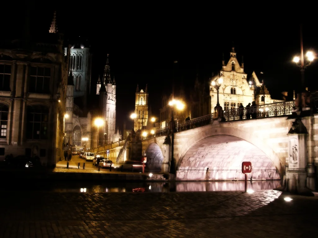 St Michael's Bridge and the riverside buildings of Ghent lit up at night.