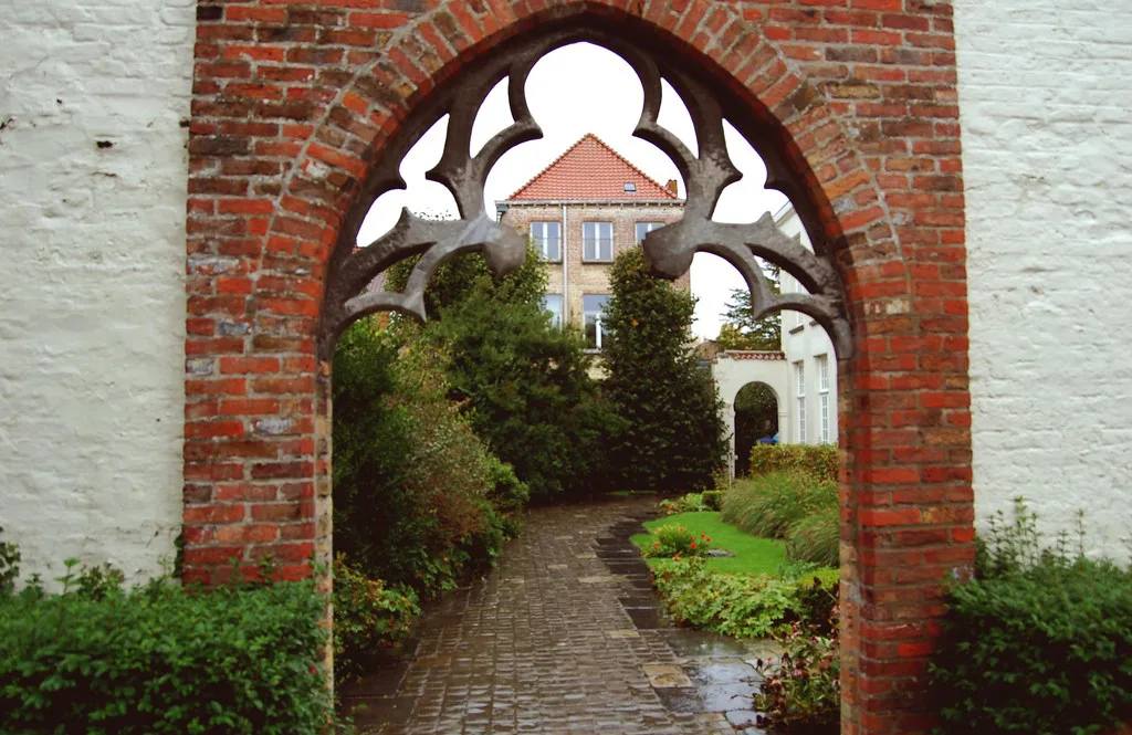 A Gothic brick archway opening onto a garden path near the Groeningemuseum, Bruges.