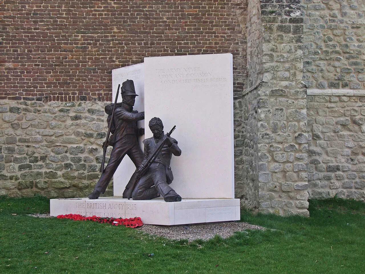 The 'Closing the Gates' memorial sculpture against the wall of Hougoumont farm, Braine-l'Alleud.