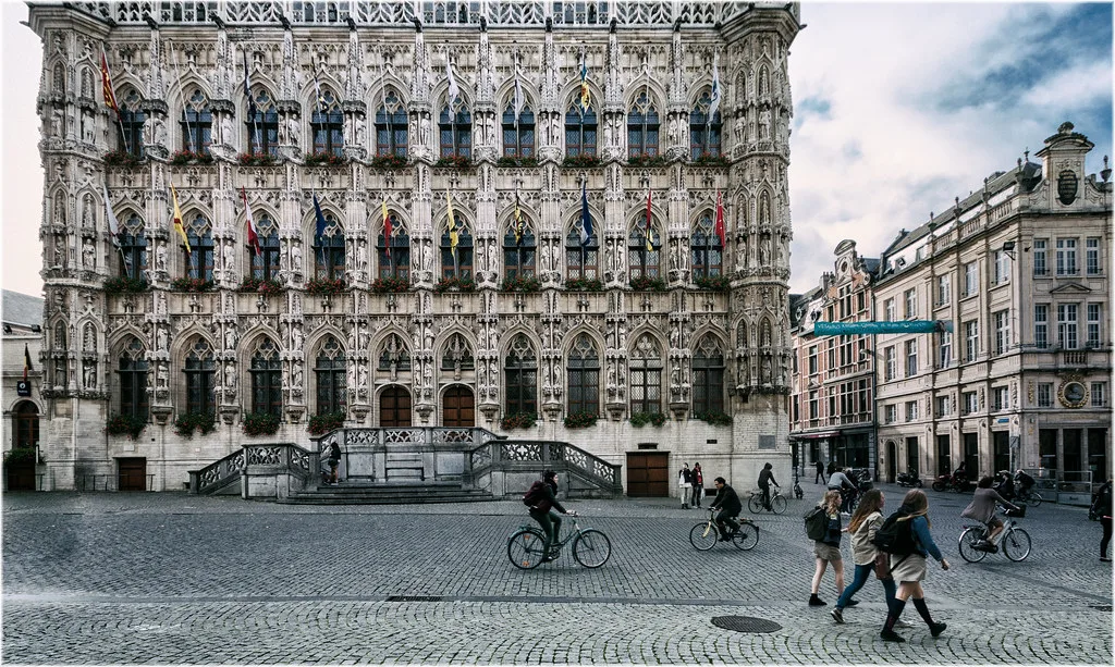 Cyclists passing Leuven Town Hall on the Grote Markt.