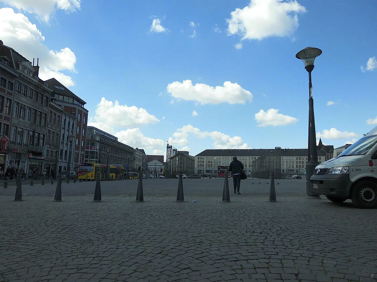 A broad cobbled square in central Liège under a blue sky.