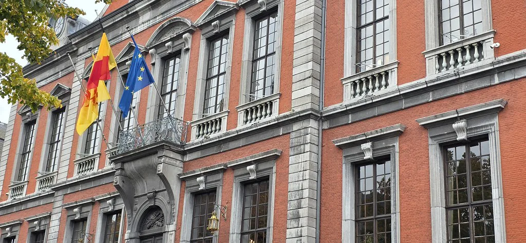 A red-brick civic façade hung with flags, Liège.