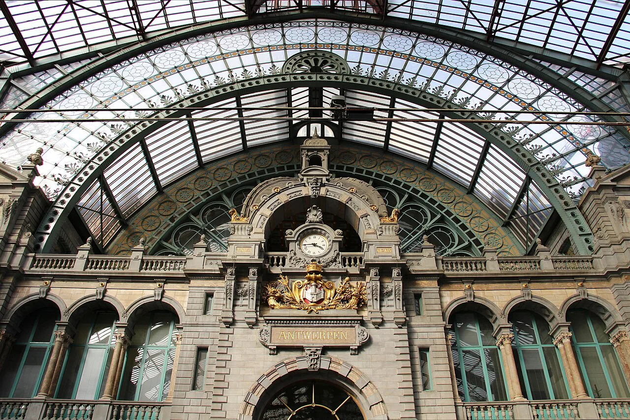 The ornate clock wall and glass roof inside the main hall of Antwerpen-Centraal station in Antwerp.