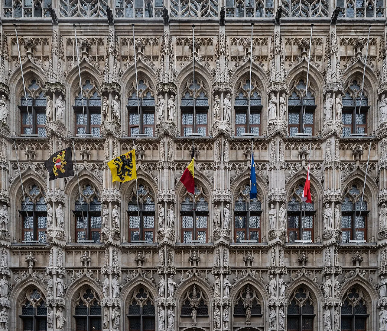 Ornate Gothic windows and niches on the facade of Leuven Town Hall.