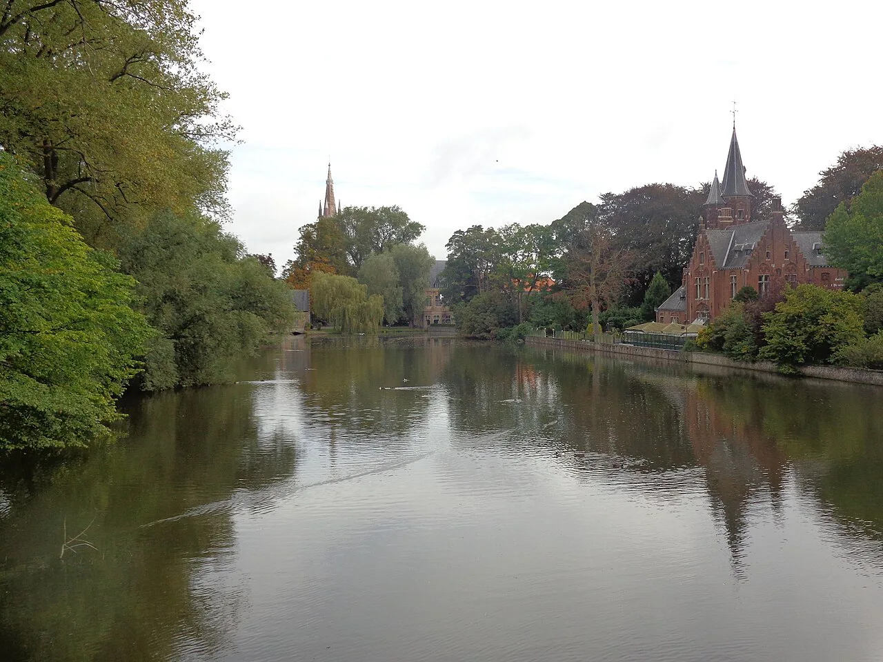 The Minnewater in Bruges, with church towers beyond the trees.