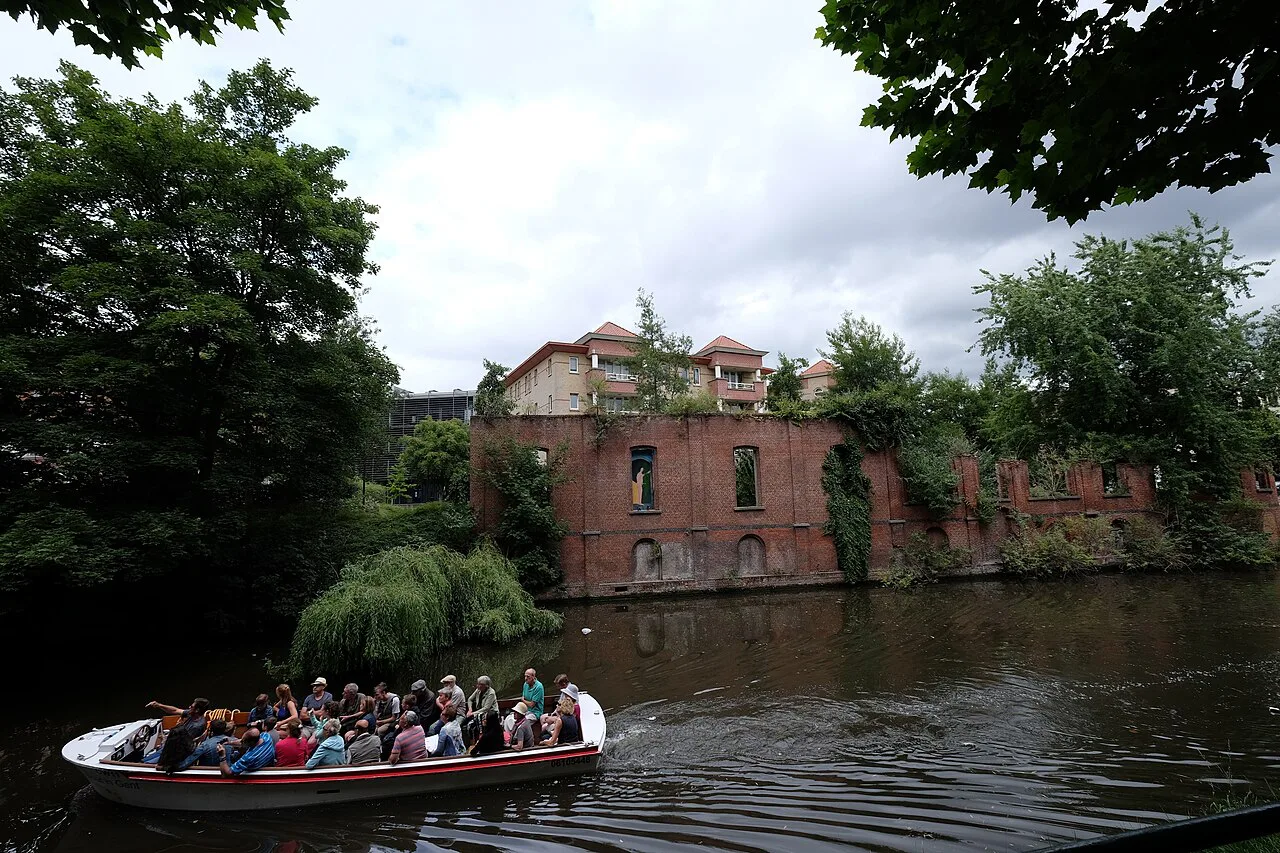 A tour boat on a tree-lined waterway in Ghent.