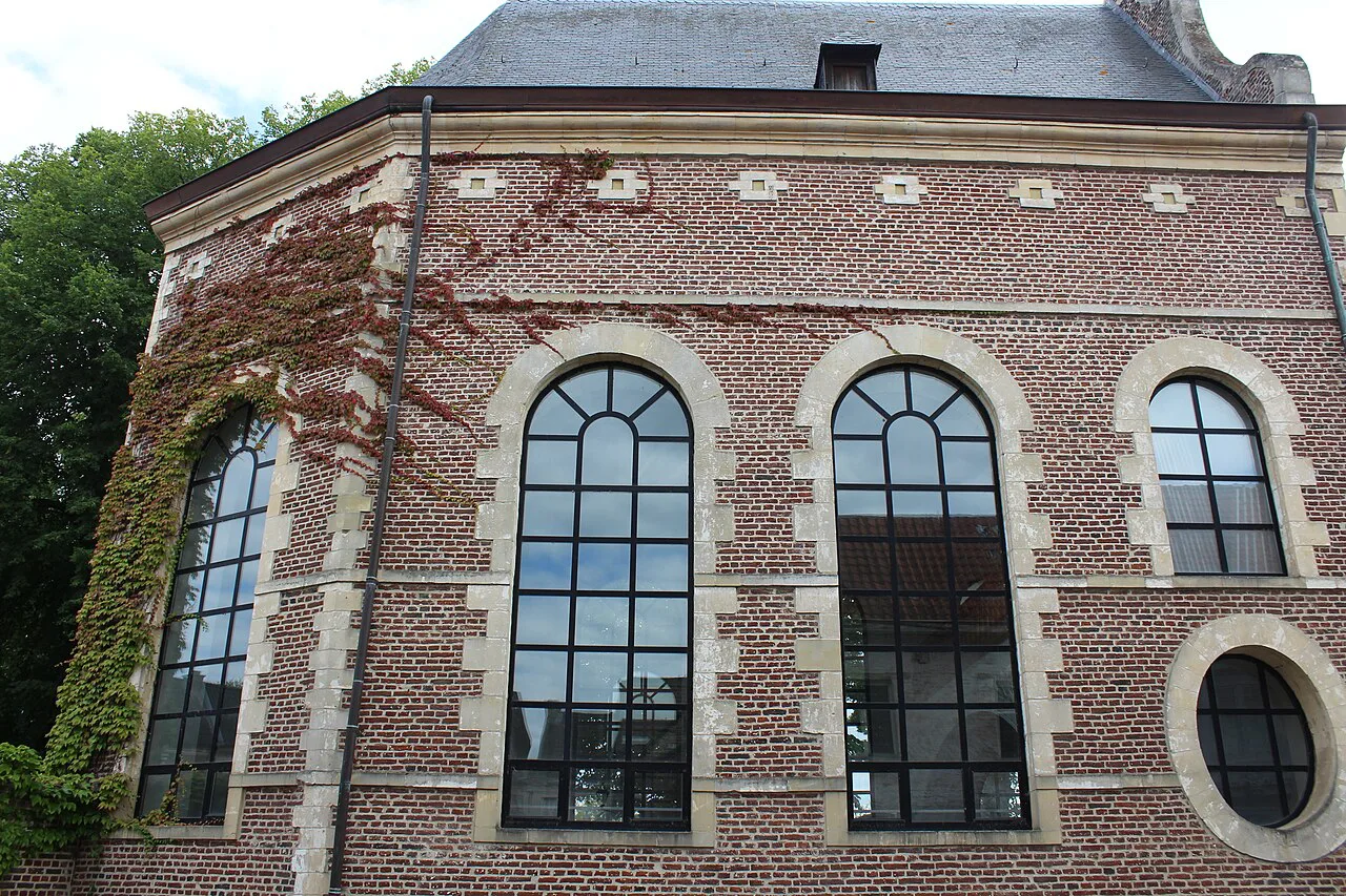 A brick and stone building with tall arched windows in Tongeren.