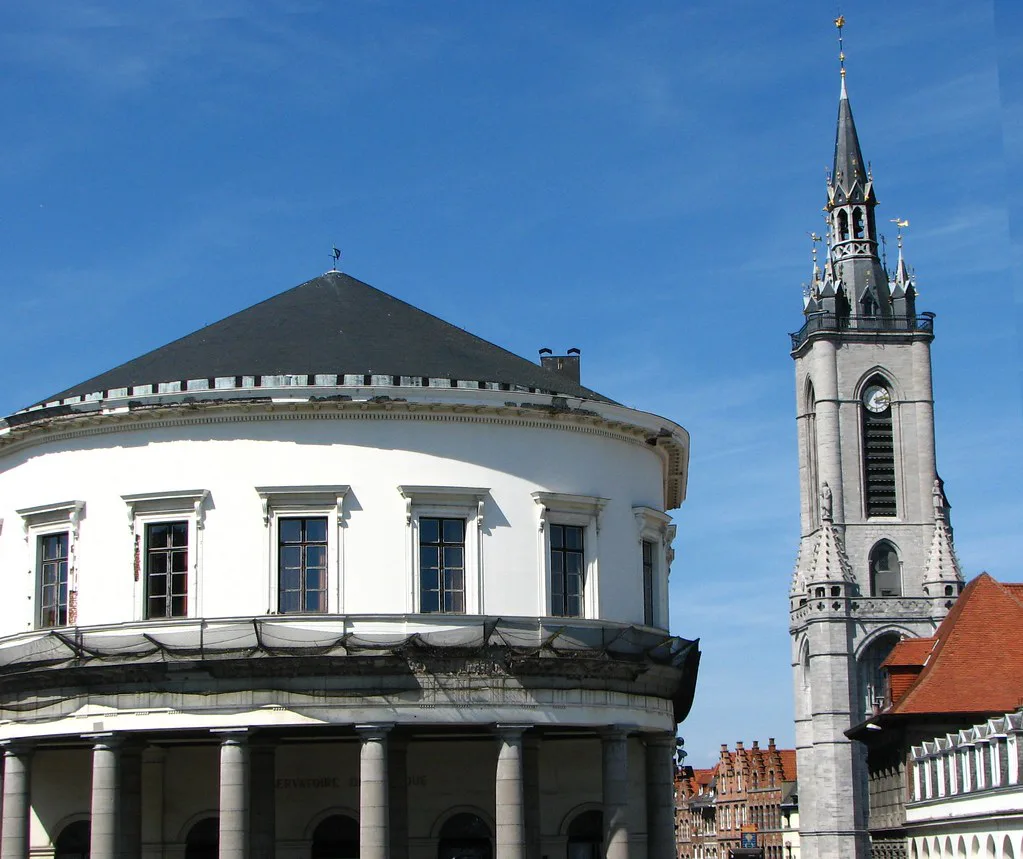 Tournai's belfry rising beside a round neoclassical building in the city centre.