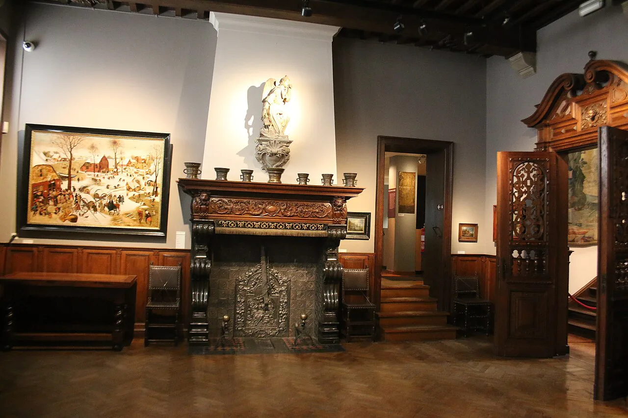 A period room with paintings and a carved fireplace inside the Museum Mayer van den Bergh in Antwerp.