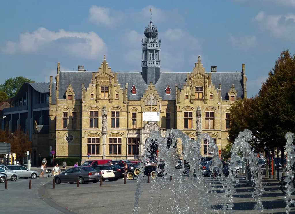 The gabled former hospital building on the Grote Markt in Ypres, now the Court of Justice, behind a fountain.